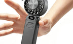 Black fan held in hand, showing scale